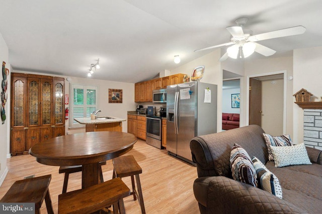 kitchen with light wood-type flooring, a sink, stainless steel appliances, light countertops, and lofted ceiling