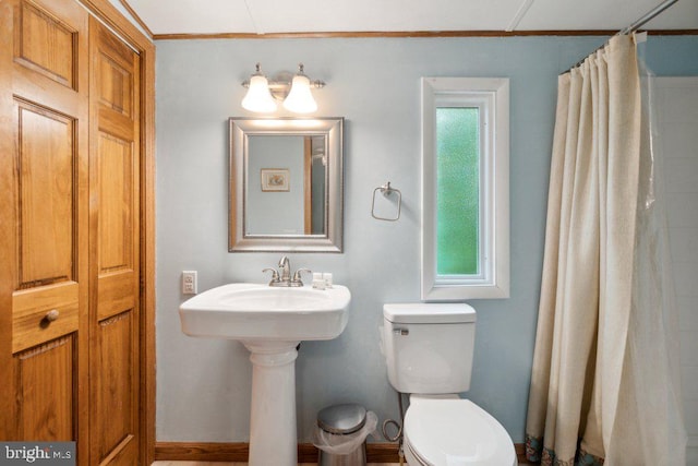 bathroom with a shower with shower curtain, toilet, a healthy amount of sunlight, and a sink