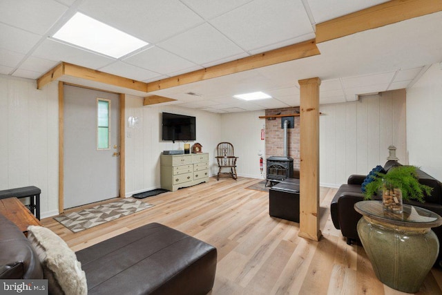 interior space with a wood stove, a paneled ceiling, and wood finished floors