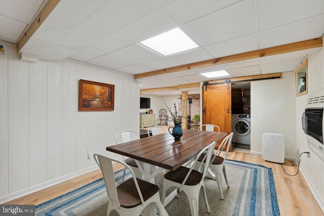 dining room with washer / clothes dryer, a paneled ceiling, and light wood finished floors