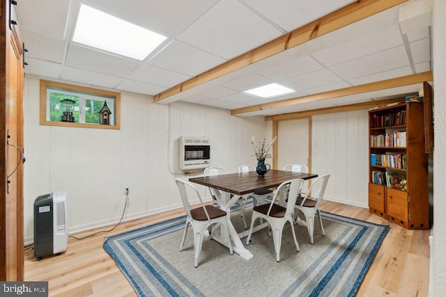 dining area with heating unit, a paneled ceiling, and light wood-style floors