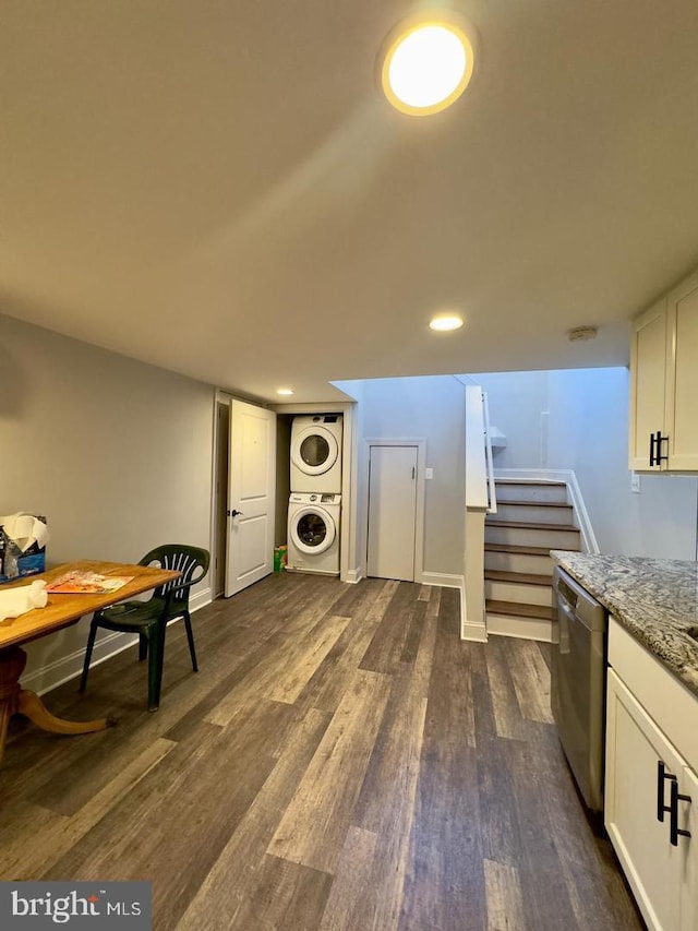 interior space featuring dark wood-style floors, light stone countertops, white cabinets, stacked washer / drying machine, and stainless steel dishwasher