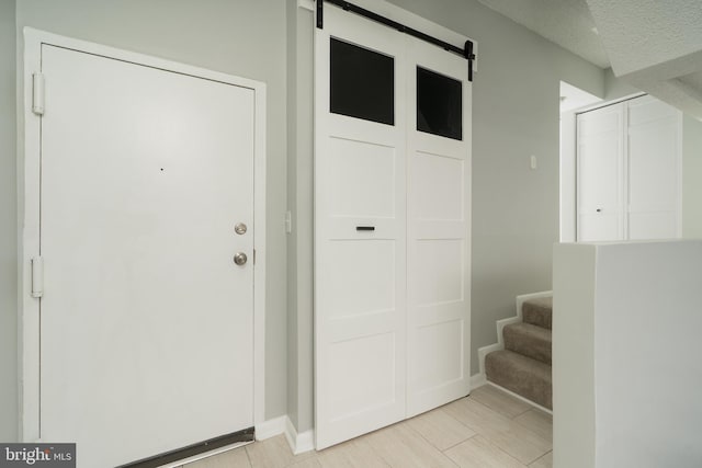 entrance foyer featuring a barn door, baseboards, a textured ceiling, and stairway