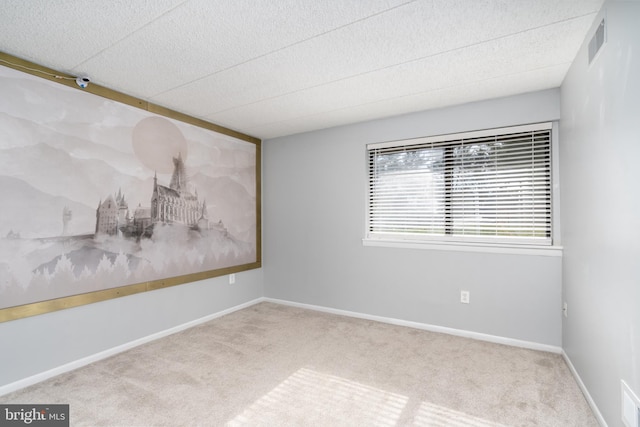 carpeted empty room featuring visible vents, a textured ceiling, and baseboards