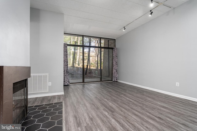 unfurnished living room with wood finished floors, baseboards, visible vents, a multi sided fireplace, and expansive windows