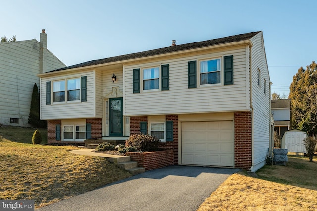 raised ranch with aphalt driveway, brick siding, and an attached garage