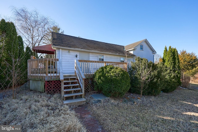 exterior space with a wooden deck, roof with shingles, and stairs