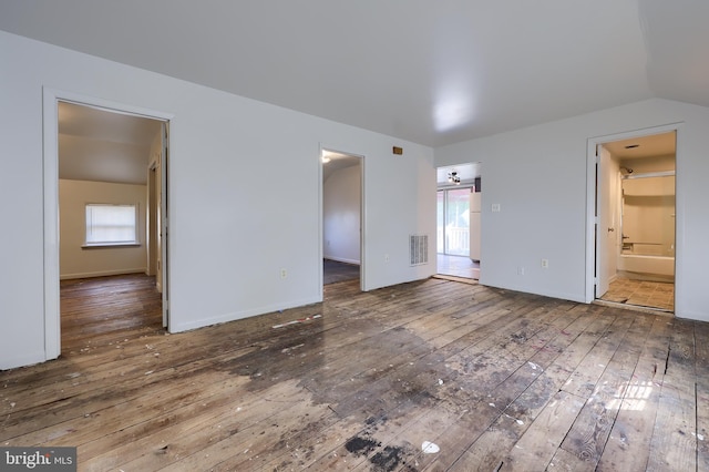 unfurnished bedroom with visible vents, lofted ceiling, hardwood / wood-style flooring, a walk in closet, and multiple windows