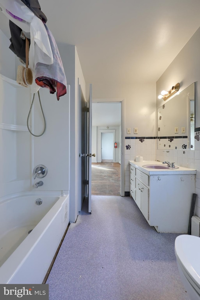 bathroom featuring carpet, tile walls, wainscoting, tub / shower combination, and vanity