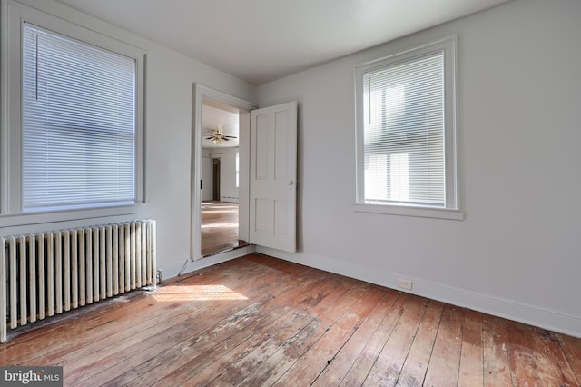 unfurnished bedroom featuring hardwood / wood-style floors, radiator heating unit, and baseboards