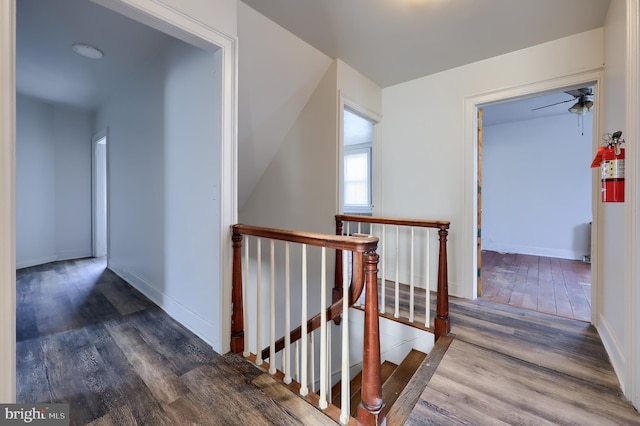 hall with an upstairs landing, baseboards, and wood finished floors