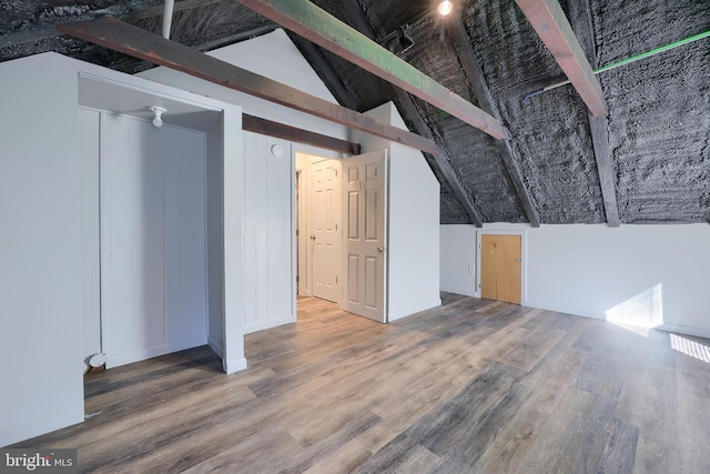 additional living space featuring lofted ceiling with beams and wood finished floors