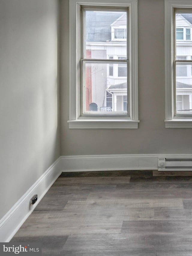 empty room featuring baseboards, baseboard heating, and wood finished floors