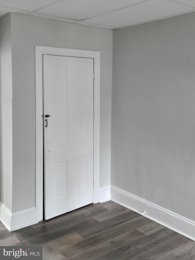 interior space featuring dark wood-style floors, baseboards, and a paneled ceiling