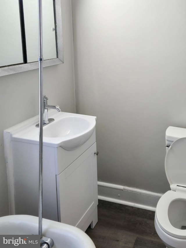 half bathroom with toilet, vanity, and wood finished floors