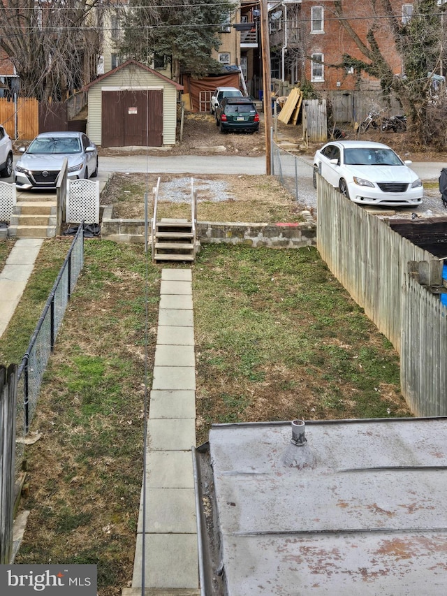 view of yard featuring a shed, an outdoor structure, and fence