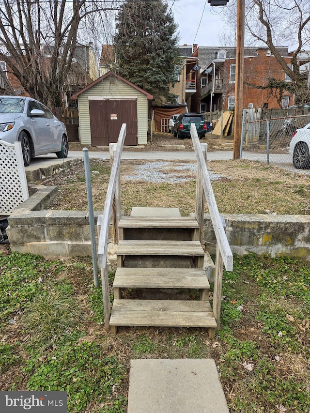 view of yard with an outbuilding, a detached garage, fence, a residential view, and a storage shed