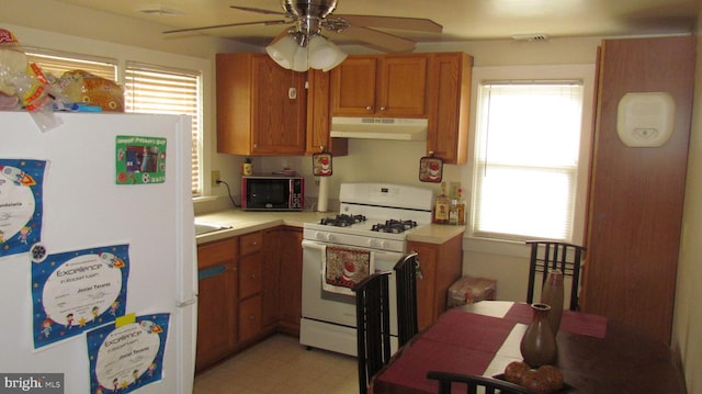 kitchen with under cabinet range hood, light floors, light countertops, brown cabinetry, and white appliances