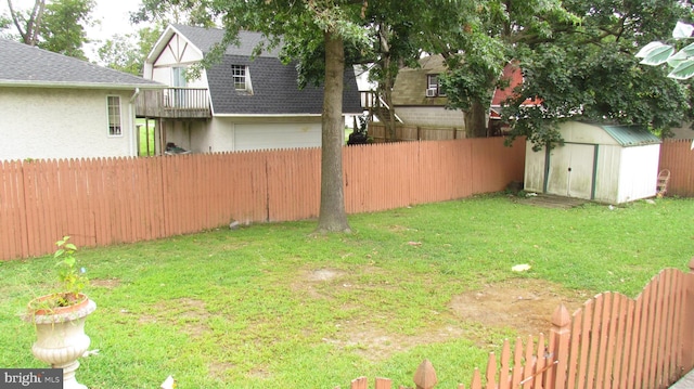 view of yard with an outdoor structure, an attached garage, a fenced backyard, and a shed