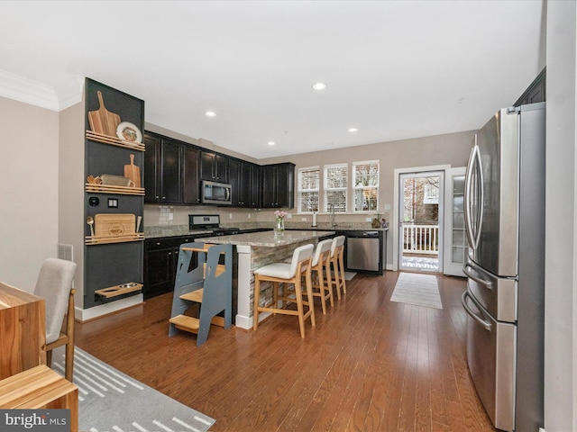 kitchen with open shelves, a center island, dark cabinets, stainless steel appliances, and dark wood-style flooring