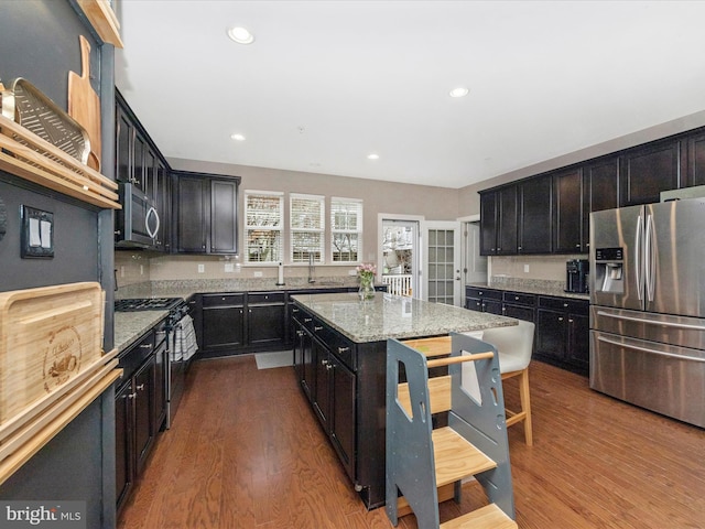 kitchen featuring recessed lighting, light stone countertops, appliances with stainless steel finishes, and dark wood-style flooring