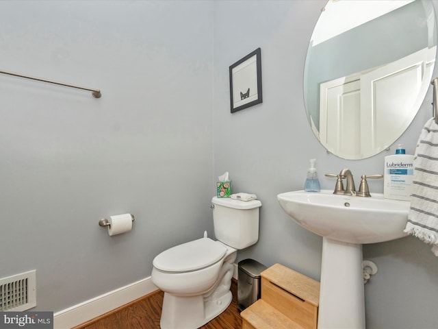 half bathroom featuring visible vents, toilet, baseboards, and wood finished floors