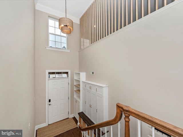 foyer with dark wood finished floors, crown molding, a notable chandelier, and baseboards