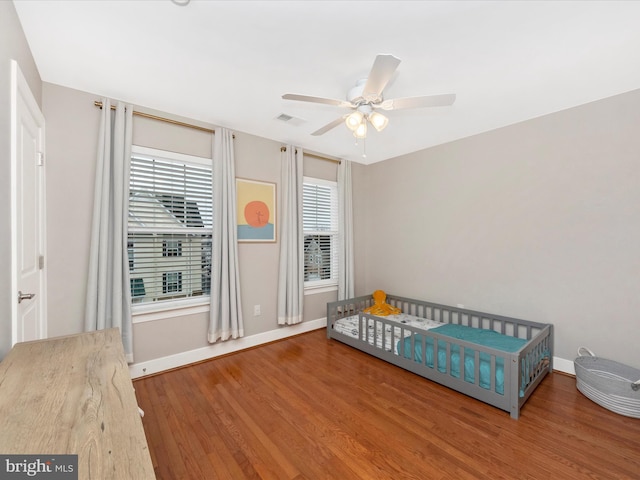 bedroom with visible vents, baseboards, wood finished floors, and a ceiling fan