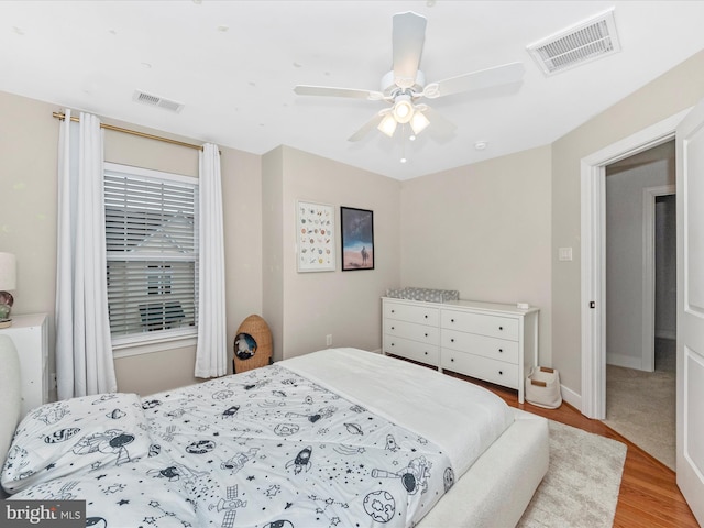 bedroom featuring ceiling fan, visible vents, baseboards, and wood finished floors