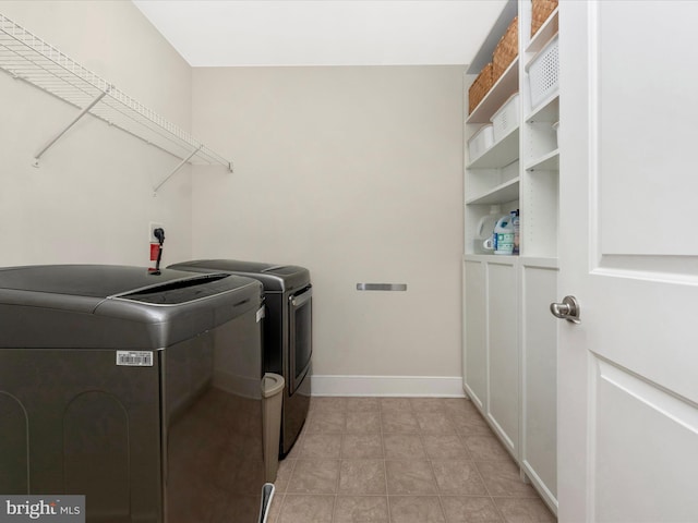 washroom featuring light tile patterned floors, baseboards, laundry area, and washing machine and clothes dryer