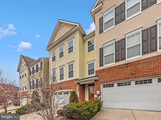 townhome / multi-family property with brick siding, a garage, and driveway