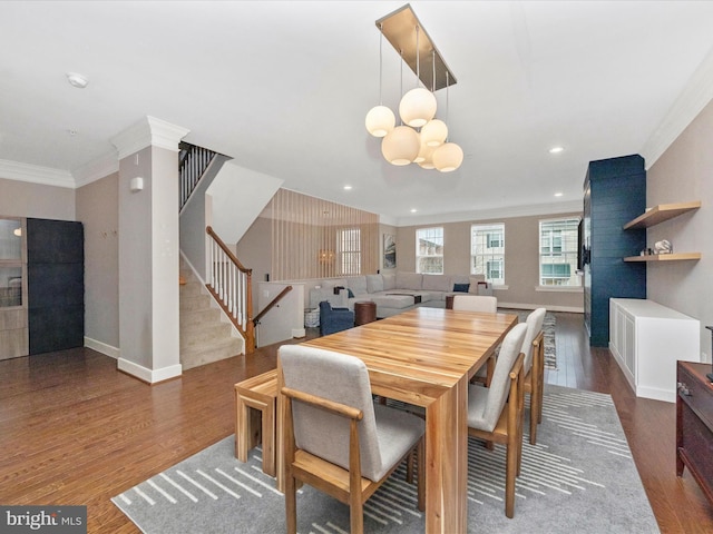 dining space featuring ornamental molding, wood finished floors, baseboards, a chandelier, and stairs