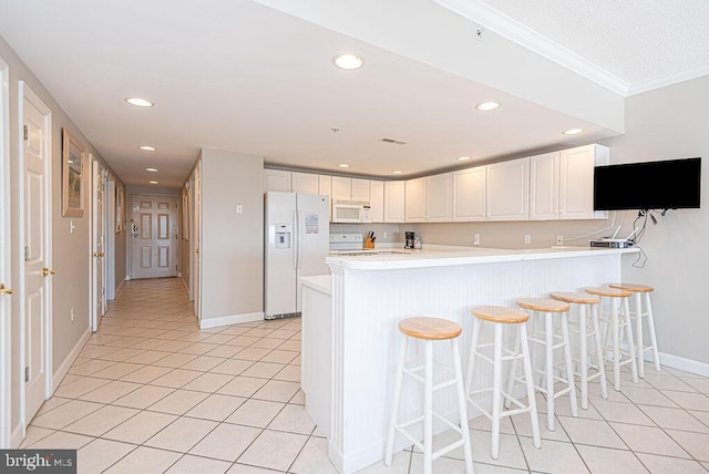 kitchen featuring light tile patterned flooring, white appliances, light countertops, and a peninsula