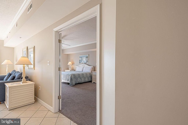 corridor featuring visible vents, light carpet, a textured ceiling, light tile patterned flooring, and baseboards