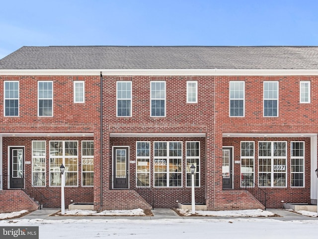 snow covered rear of property with brick siding