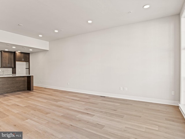 unfurnished living room featuring recessed lighting, light wood-type flooring, and baseboards