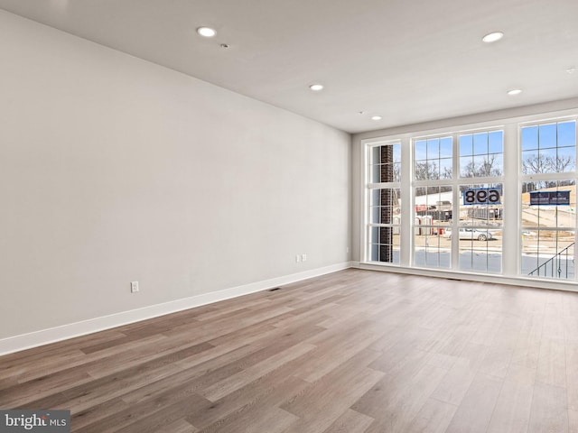 spare room with recessed lighting, wood finished floors, and baseboards