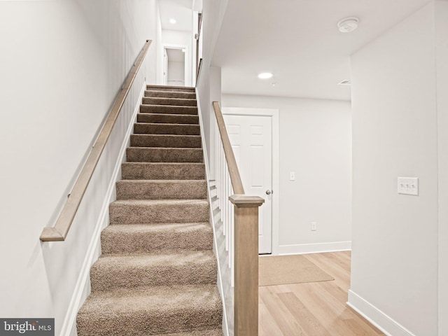 staircase with recessed lighting, wood finished floors, and baseboards