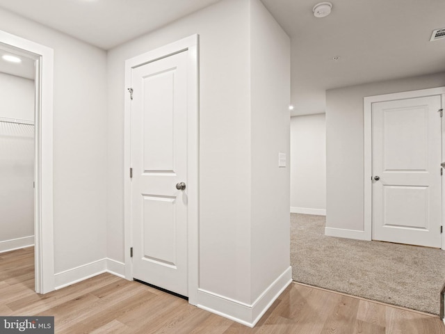 corridor with visible vents, light wood-type flooring, and baseboards