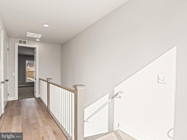 hall with an upstairs landing, visible vents, light wood finished floors, and baseboards