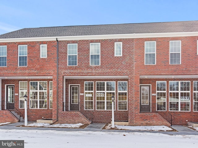 snow covered property with brick siding