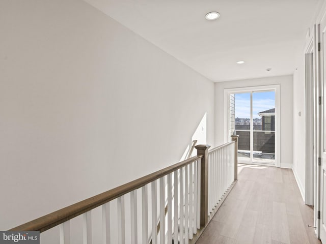 hall with an upstairs landing, recessed lighting, light wood-style flooring, and baseboards