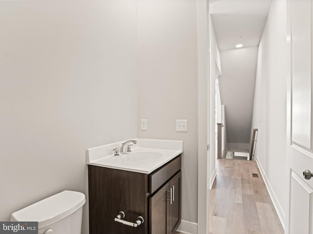 bathroom featuring vanity, toilet, wood finished floors, and baseboards