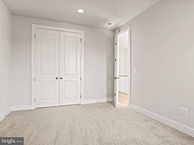 unfurnished bedroom with a closet, recessed lighting, baseboards, and carpet floors