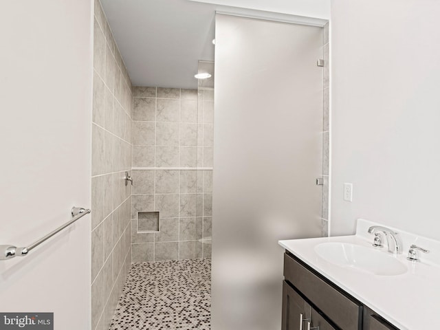 full bathroom with a tile shower and vanity