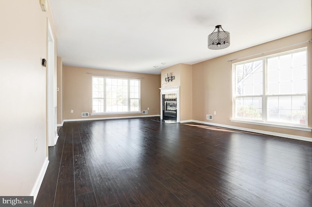 unfurnished living room featuring visible vents, wood finished floors, baseboards, and a tile fireplace