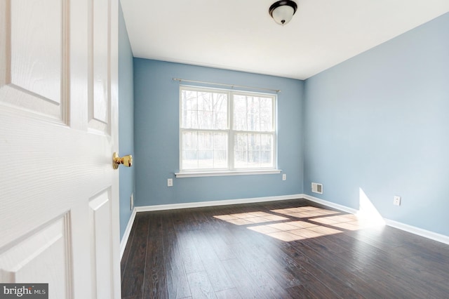 spare room featuring visible vents, baseboards, and hardwood / wood-style flooring