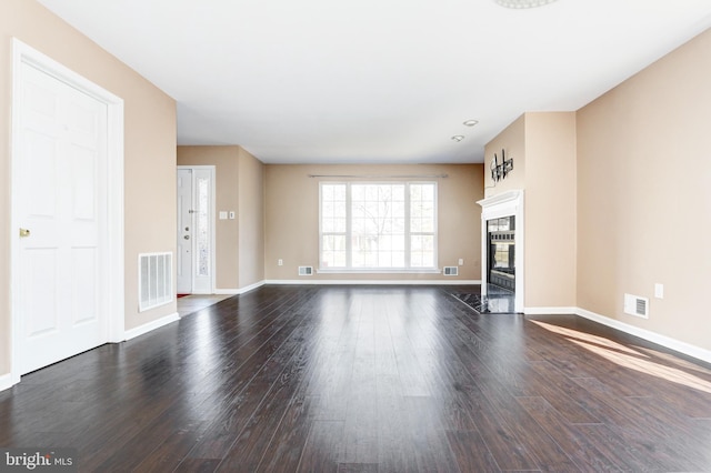 unfurnished living room with visible vents, baseboards, dark wood-type flooring, and a premium fireplace