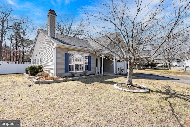 view of front of property with a front yard, a shingled roof, a chimney, and fence