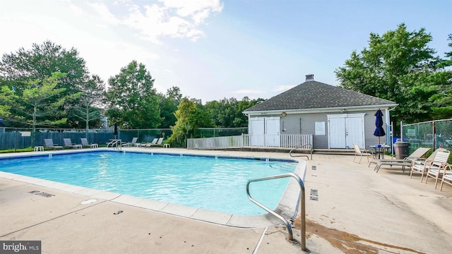 community pool featuring a patio area, an outdoor structure, and fence